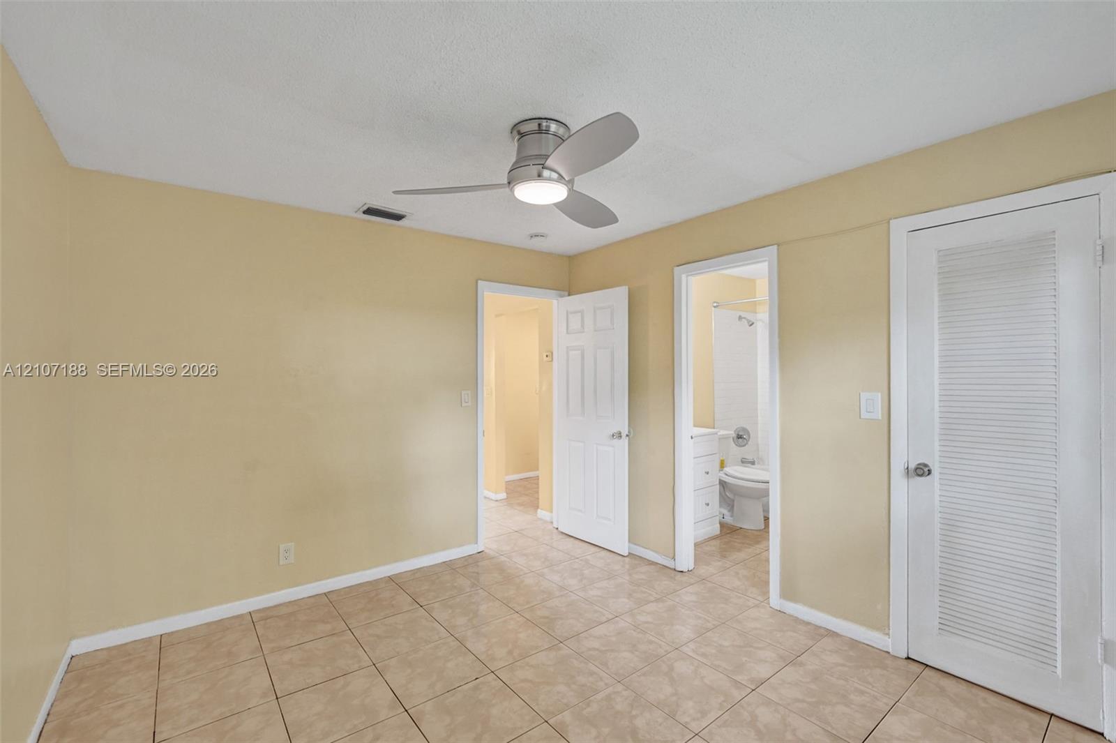 Room featuring tile flooring, a brushed nickel ceiling fan with integrated lighting, and louvered closet doors