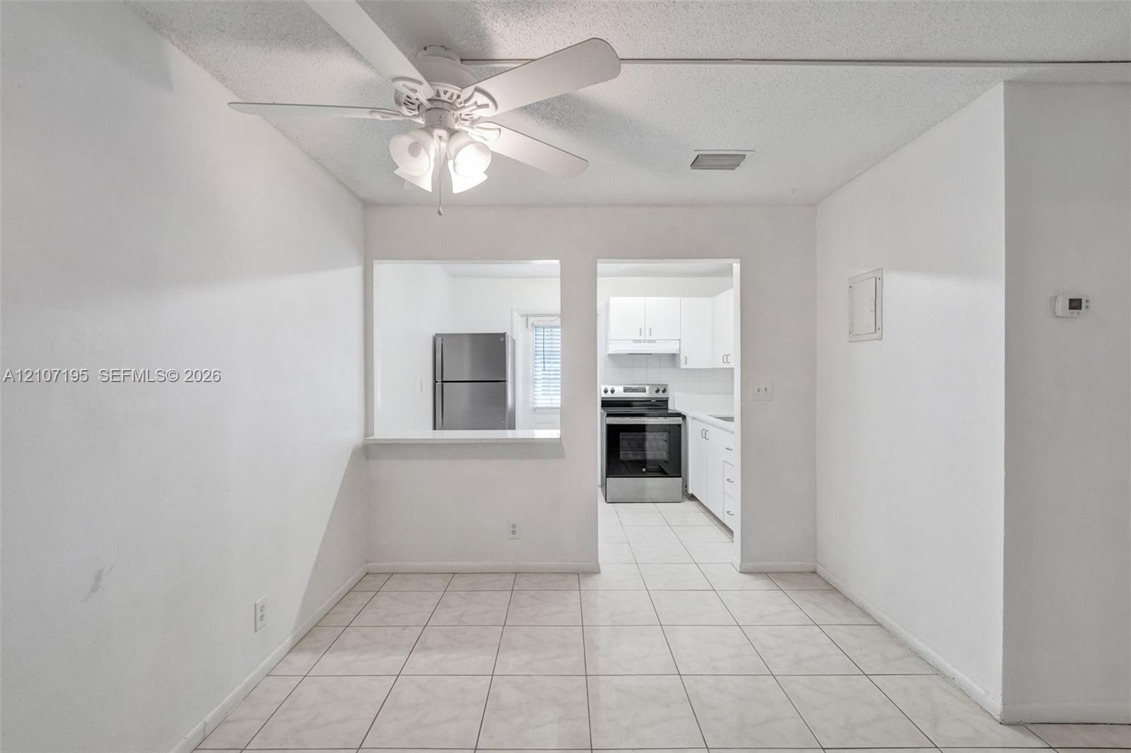 Ceramic tile flooring, white cabinetry, stainless steel kitchen appliances, and ceiling fan with integrated lighting