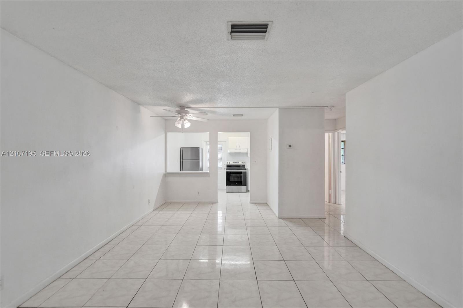 Interior space featuring neutral wall tones, large-format ceramic tile flooring, and a ceiling-mounted fan