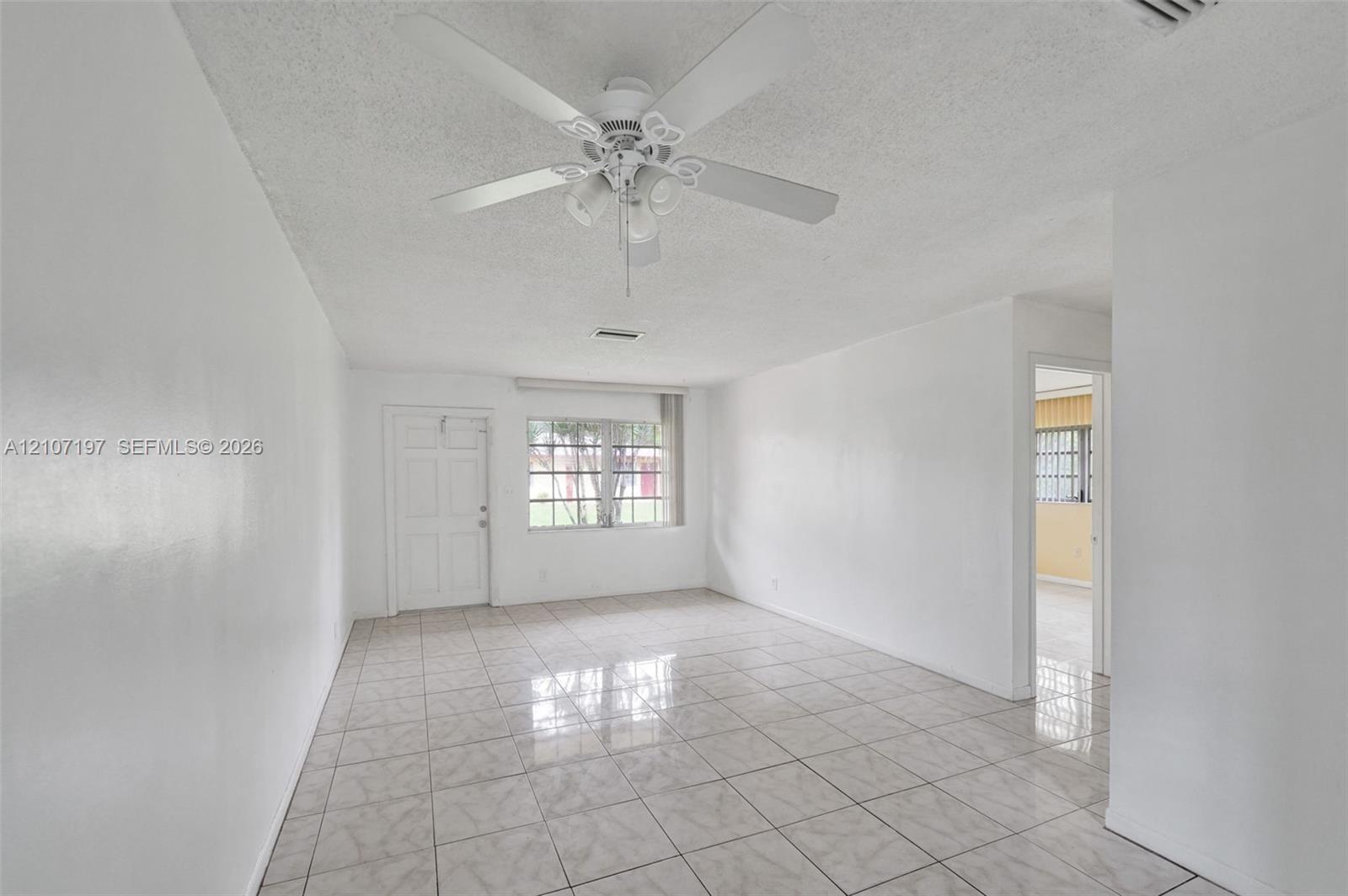 Interior space featuring tile flooring, a multi-blade ceiling fan with integrated lighting, and a multi-pane window