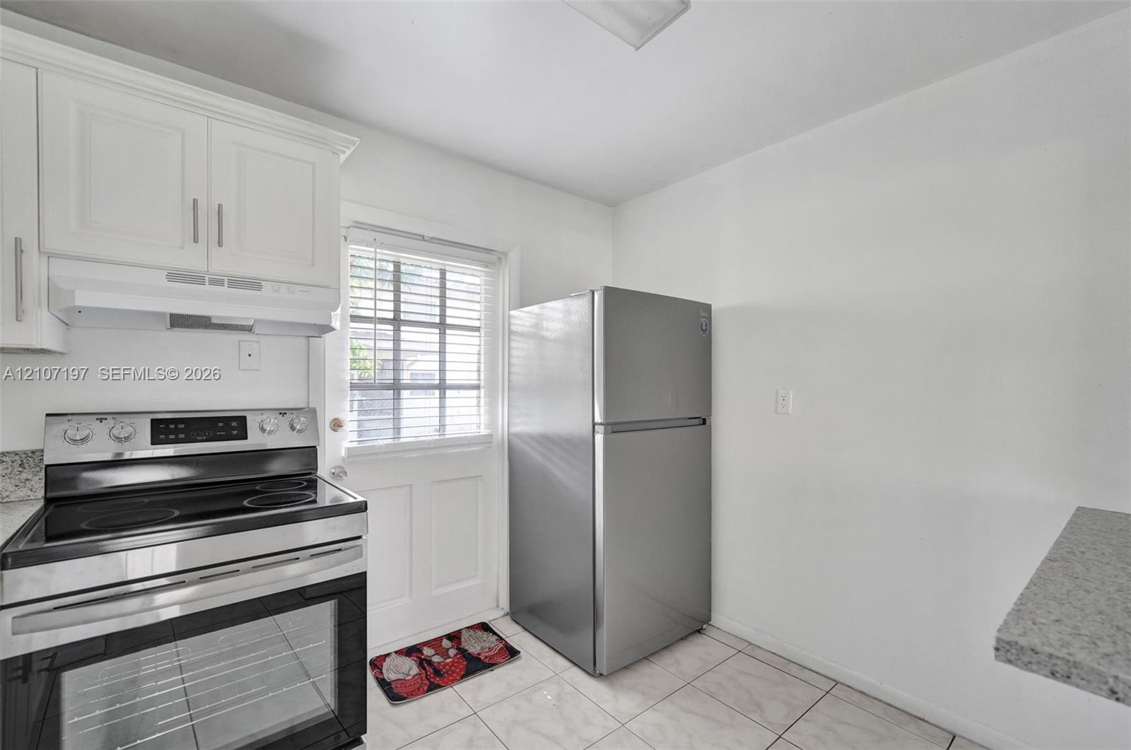 Kitchen featuring white cabinetry, stainless steel electric range with hood, stone-finish countertops, and light-toned tile flooring