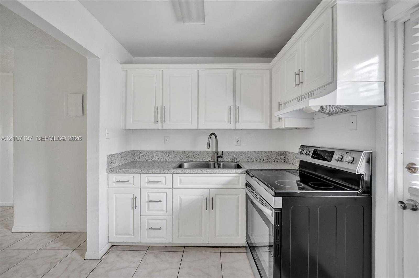 Kitchen featuring white shaker-style cabinetry, stone-finish countertops, stainless steel undermount sink with a gooseneck faucet, black electric range, and tiled flooring