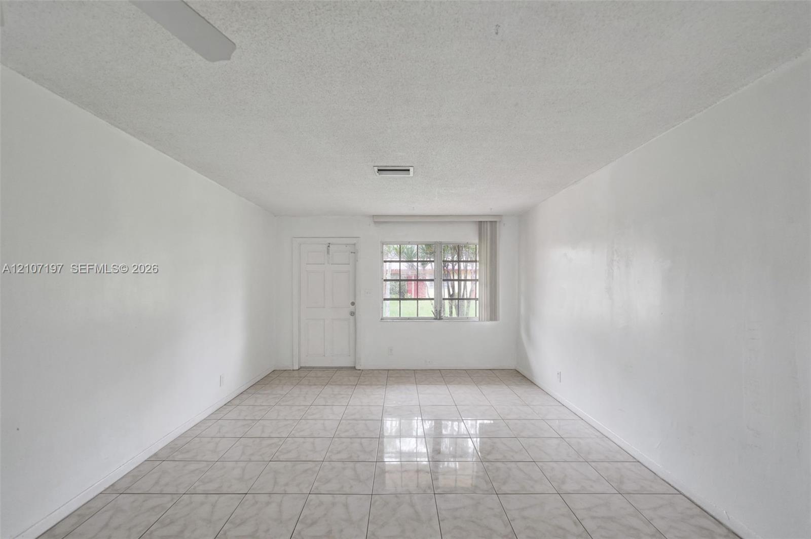 Interior space featuring neutral wall tones, large-format ceramic tile flooring, a multi-pane window, and a paneled entry door
