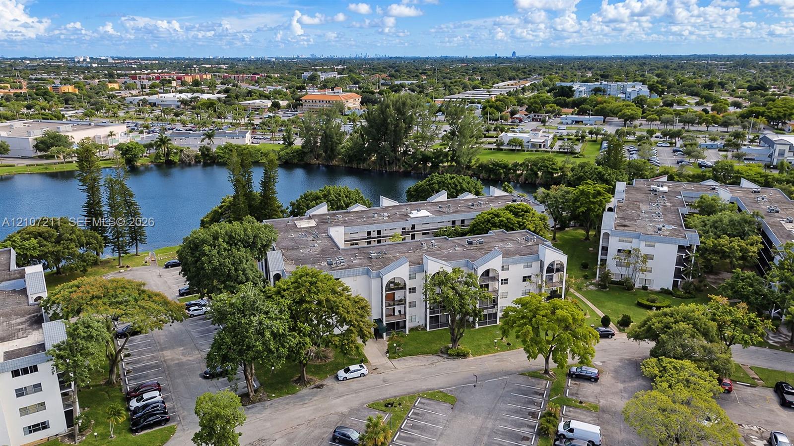 Multi-story residential complex featuring arched architectural details, private balconies, on-site parking, and water frontage with mature trees