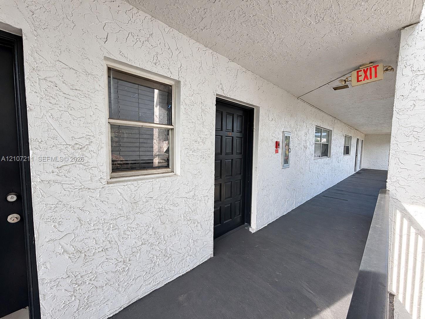 Textured stucco exterior wall with inset multi-pane entry doors and slider windows