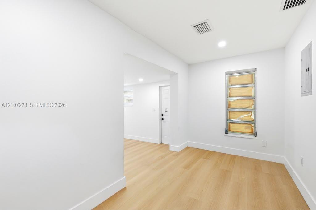 Interior space featuring wood-finish flooring, recessed lighting, and a multi-pane louvered window