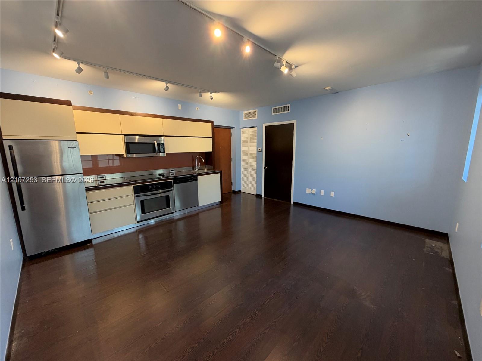 Kitchen featuring flat-panel cabinetry, stainless steel appliances, wood-finish flooring, and multi-point ceiling track lighting