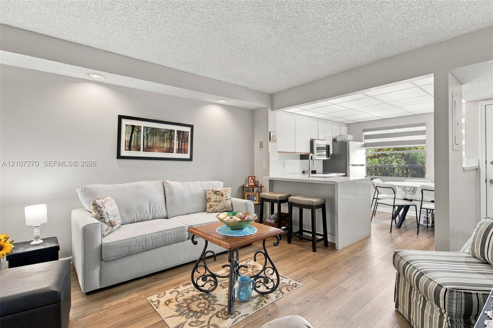 Living area featuring wood-finish flooring, recessed lighting, and a breakfast bar with stone-finish countertops