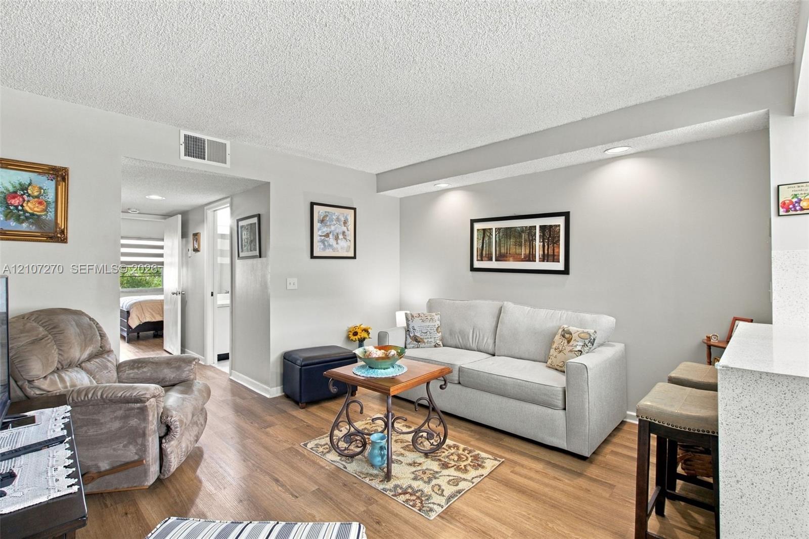 Living area featuring wood-finish flooring, recessed ceiling lighting, and a textured ceiling finish