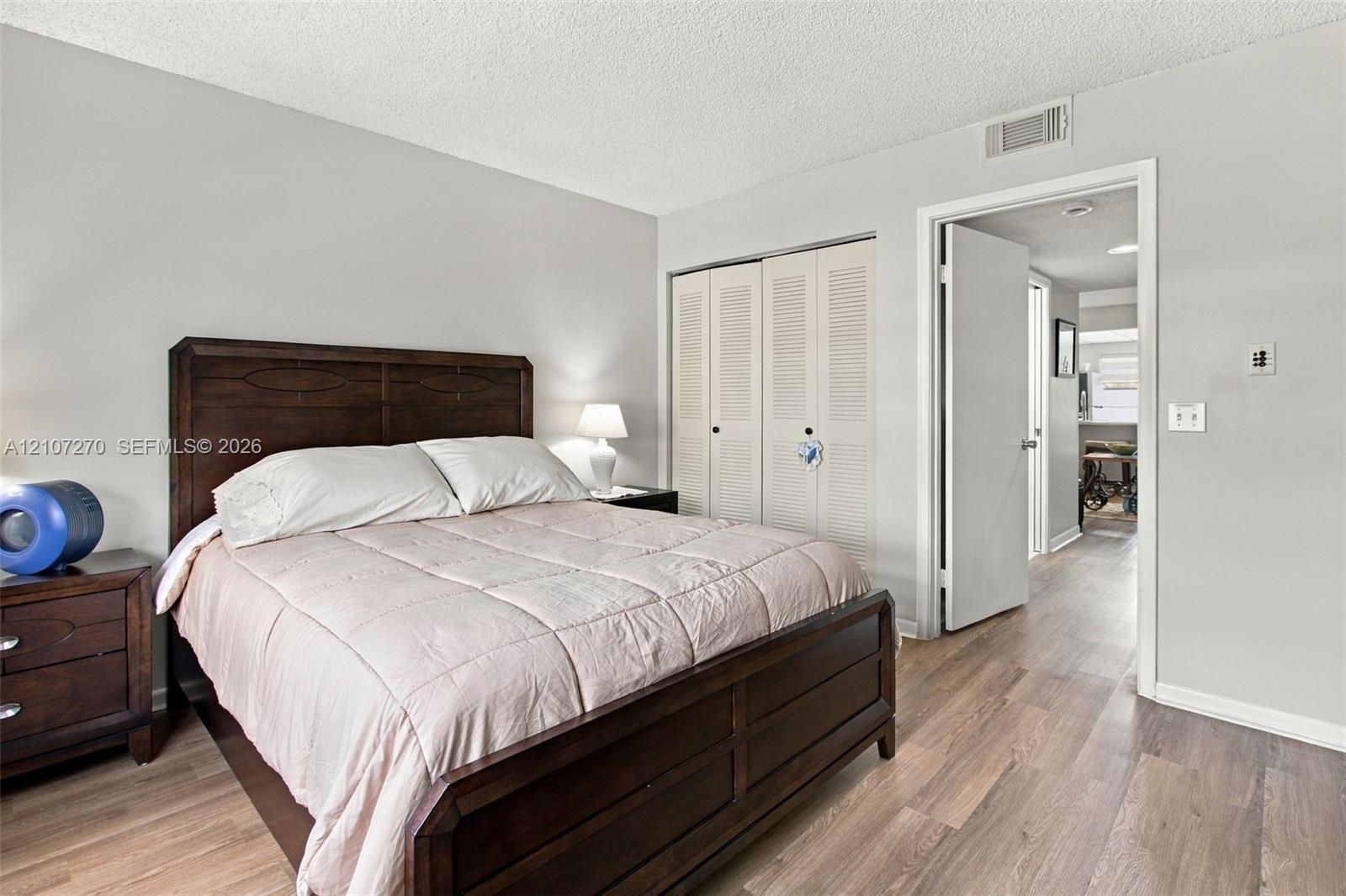 Bedroom featuring wood-finish flooring, neutral wall paint, and built-in louvered-door closets