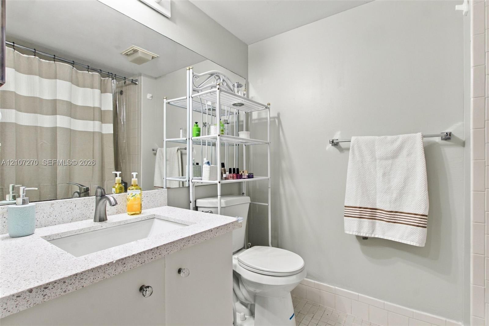 Full-width vanity featuring a stone-composite countertop, integrated sink, matte finish faucet, and expansive wall-mounted mirror