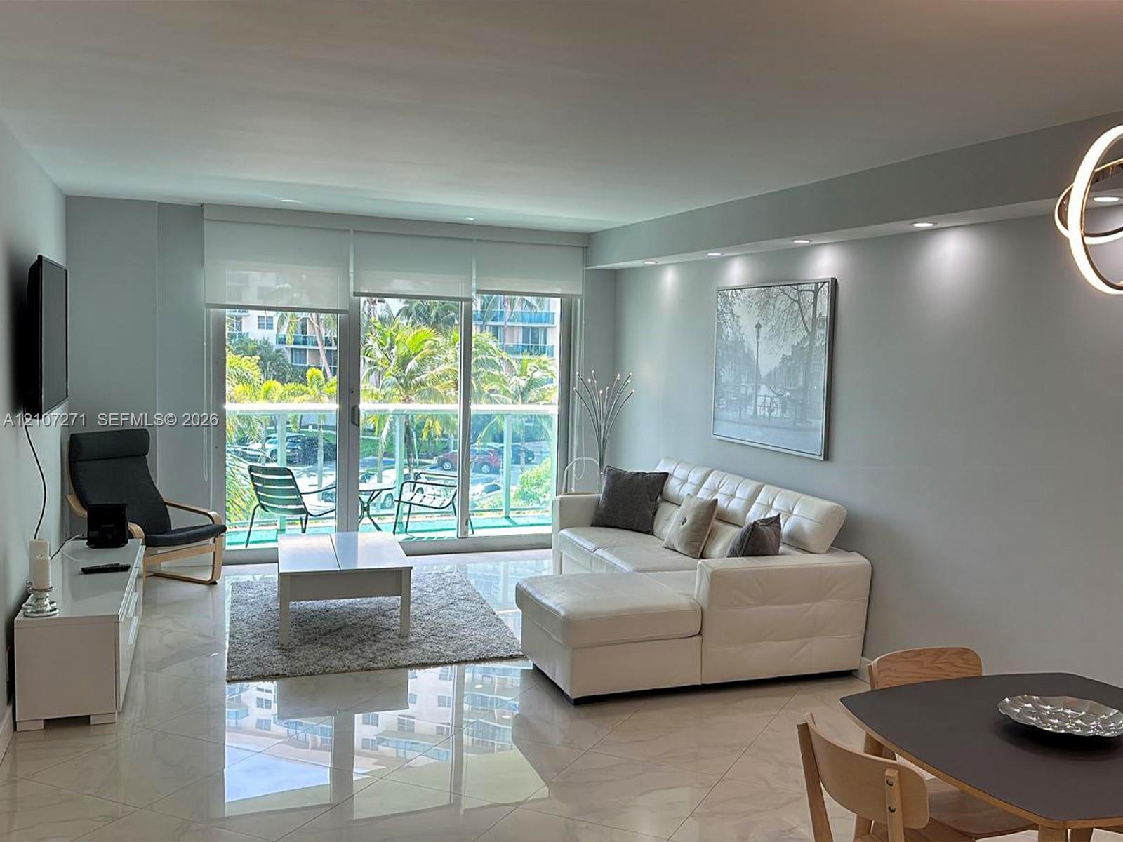 Polished tile flooring, recessed ceiling lighting, and expansive floor-to-ceiling glass doors opening to a balcony