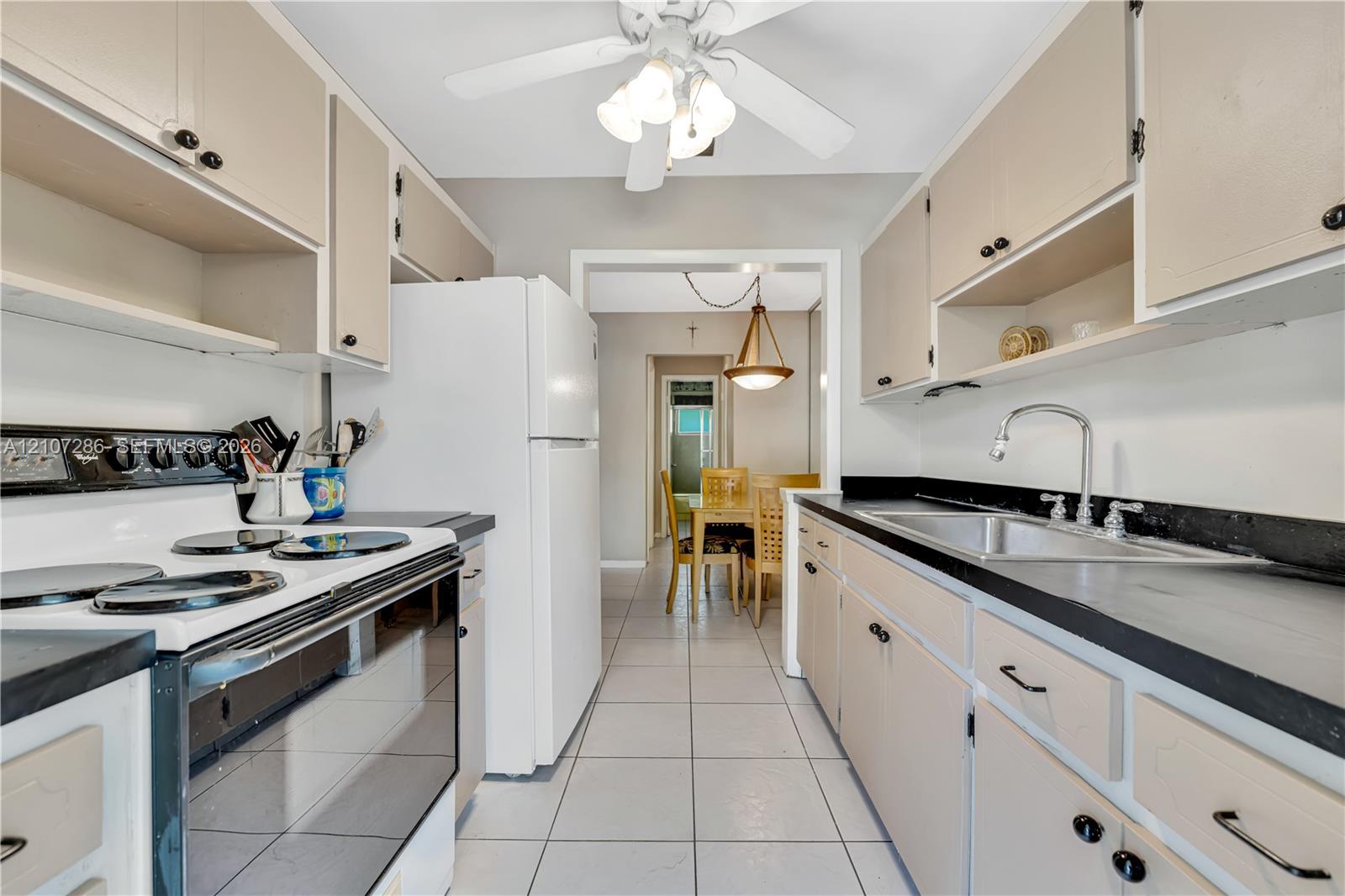 Kitchen featuring flat-panel cabinetry, dark solid-surface countertops, tile flooring, and ceiling-mounted lighting