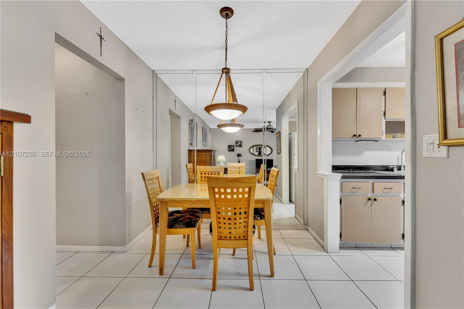 Dining area featuring ceramic tile flooring, floor-to-ceiling mirrored wall panels, and a tiered pendant light fixture