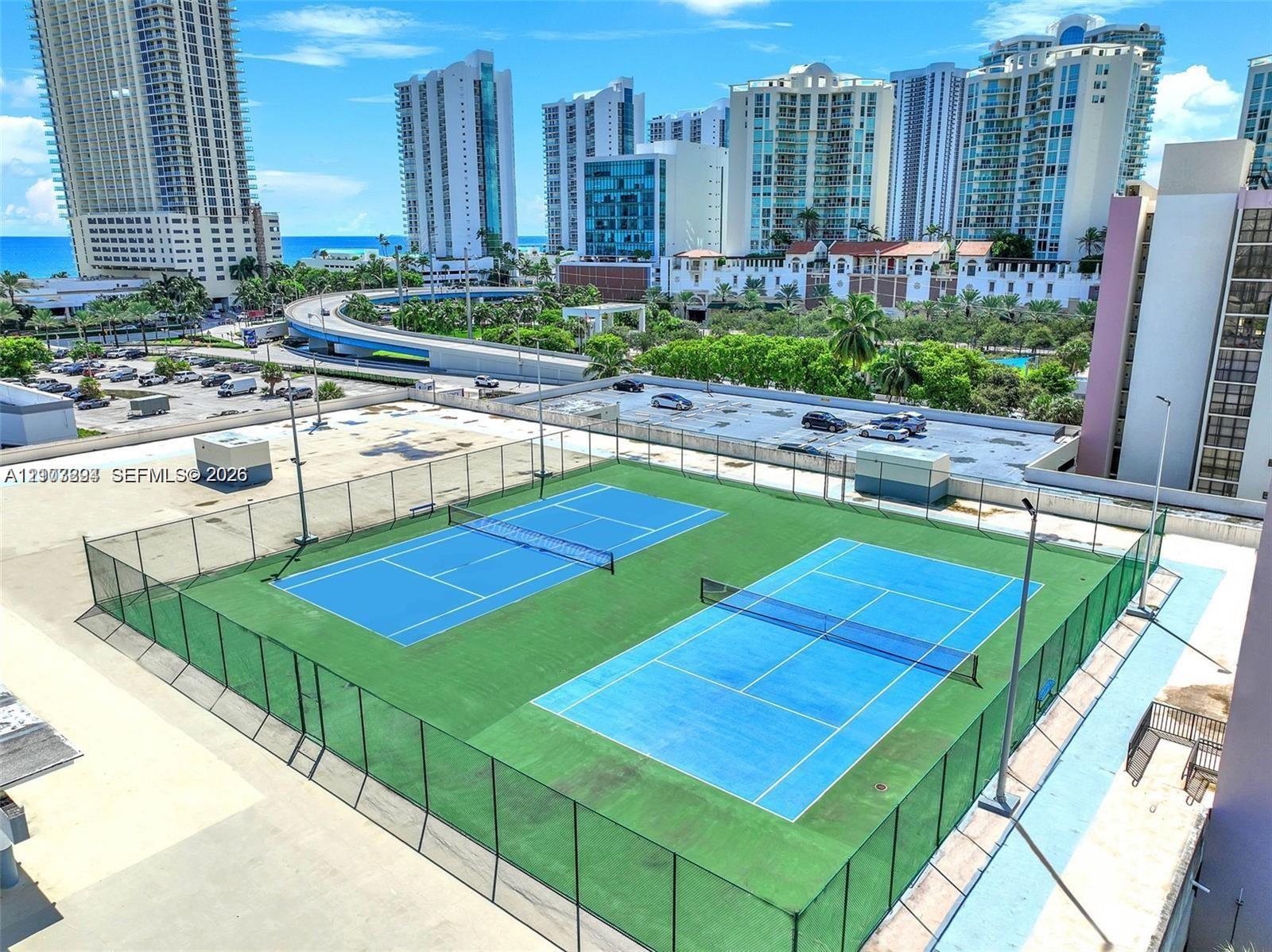 Dual tennis courts with perimeter fencing and elevated high-mast lighting