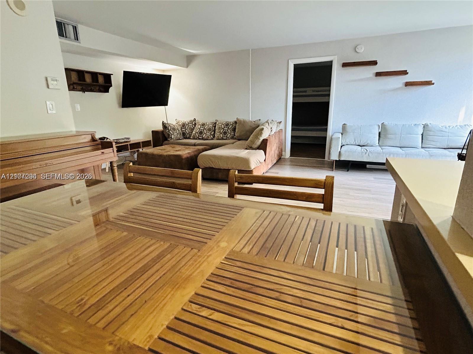 Open living area featuring wood-finish flooring, built-in wall shelving, and neutral wall tones