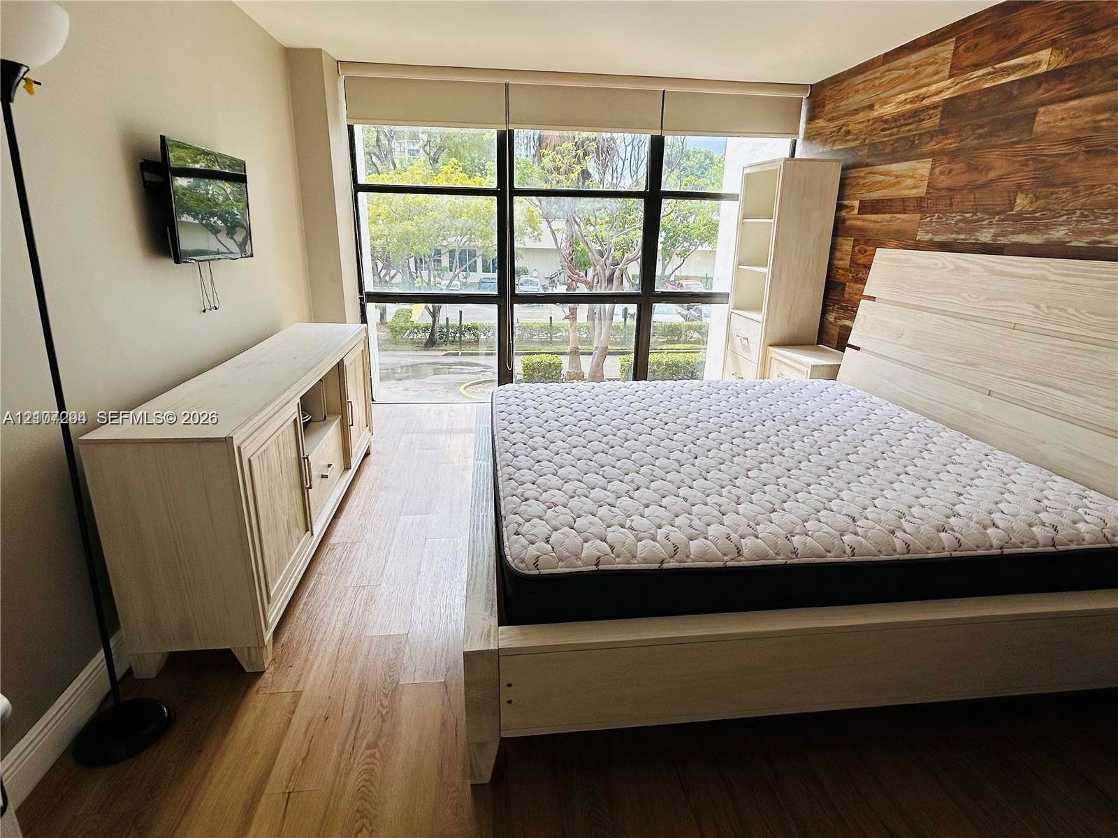 Wood-finish flooring, floor-to-ceiling windows with grid frames, and natural wood-plank accent wall