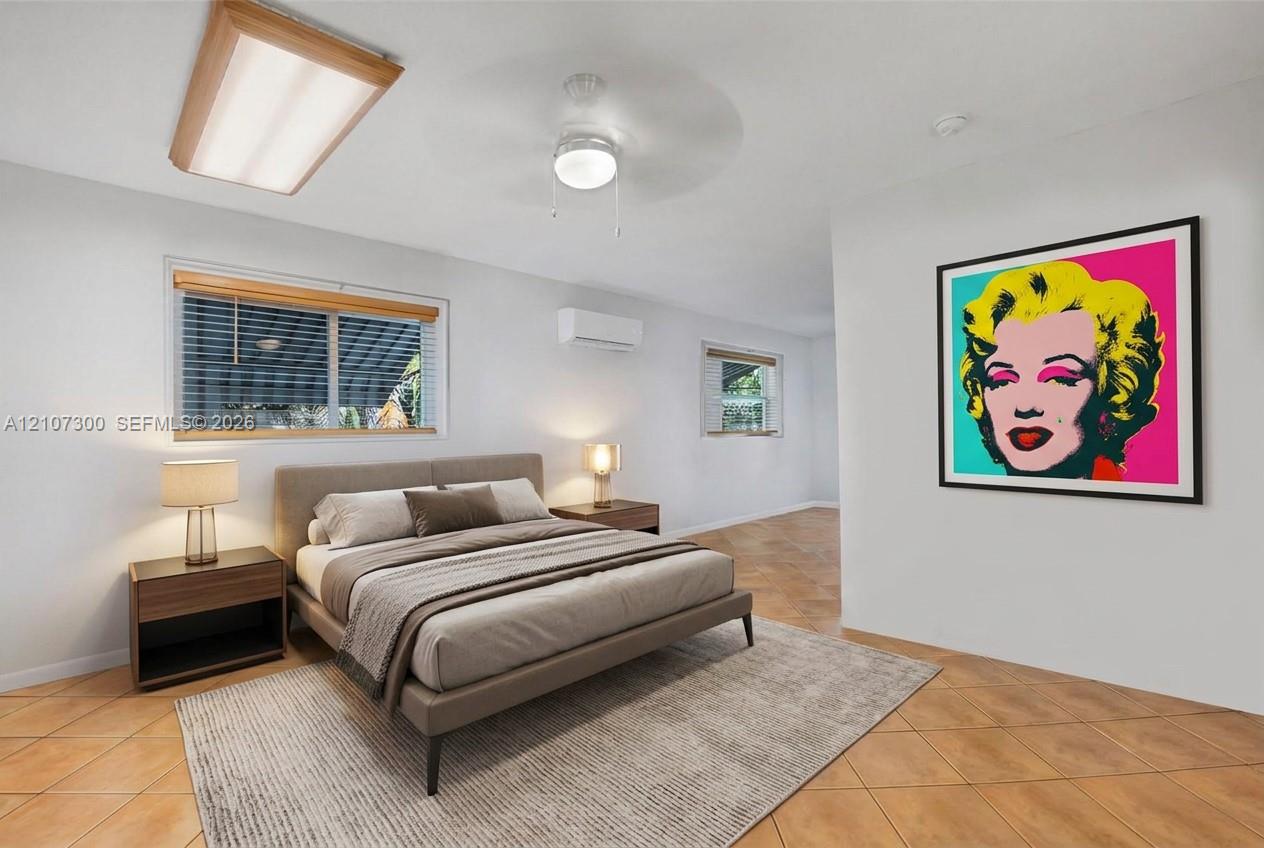 Ceramic tile flooring, wall-mounted ductless heating and cooling unit, dual-pane windows with wooden blinds, flush-mount fluorescent lighting, and a ceiling fan with integrated light fixture