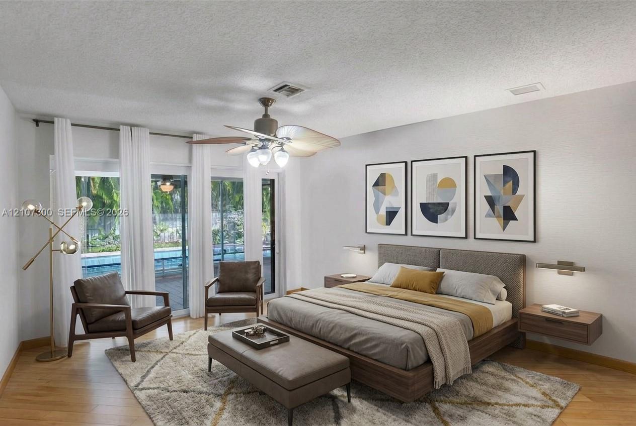 Wood-finish flooring, sliding glass doors, ceiling fan with integrated lighting, and wall-mounted light fixtures