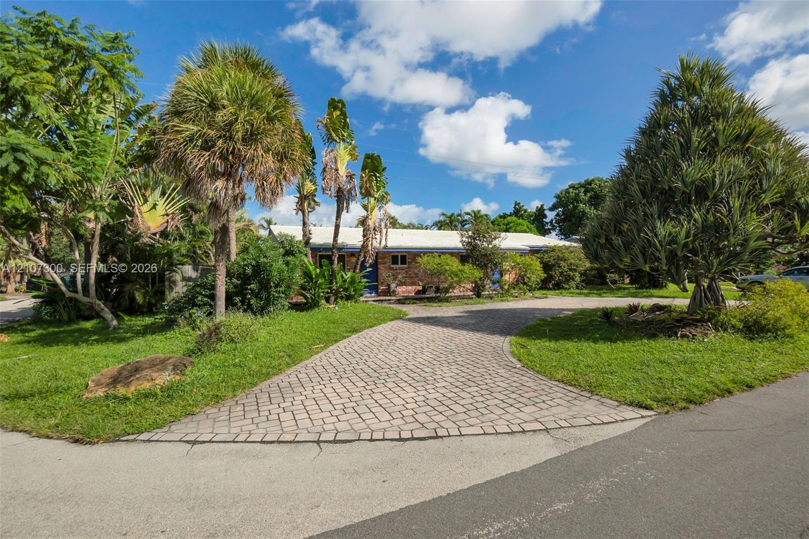 Brick exterior, paver driveway, and mature landscaping