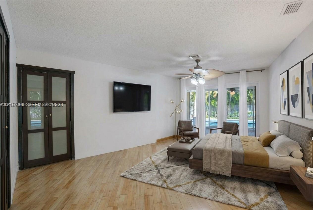 Wood-finish flooring, ceiling fan with integrated lighting, and glass-paneled closet doors