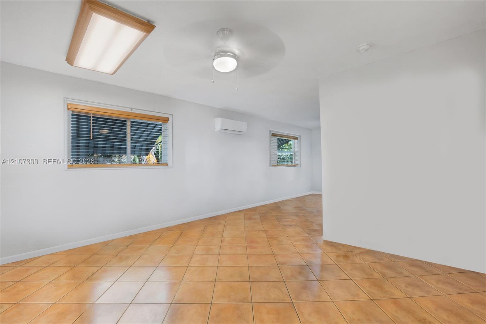 Interior space featuring tile flooring, ceiling-mounted lighting, a ceiling fan, and a wall-mounted ductless air conditioning unit