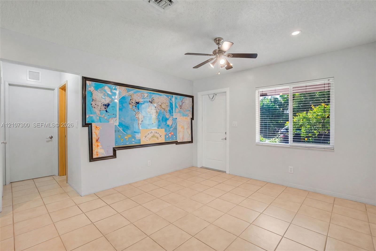 Interior space featuring neutral tile flooring, a multi-blade ceiling fan with integrated lighting, and a horizontal sliding window