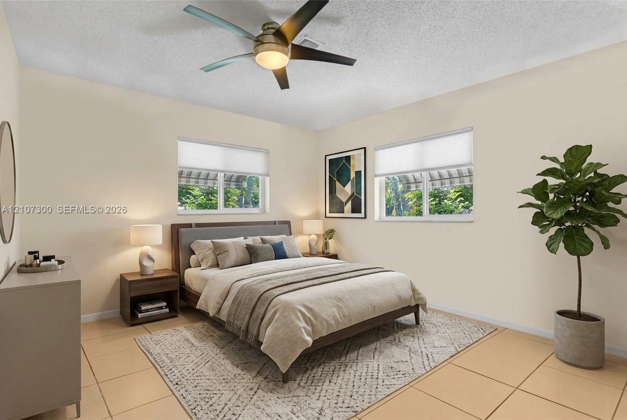 Neutral-toned interior featuring large-format floor tiles, dual windows with fitted shades, and a ceiling fan with integrated lighting