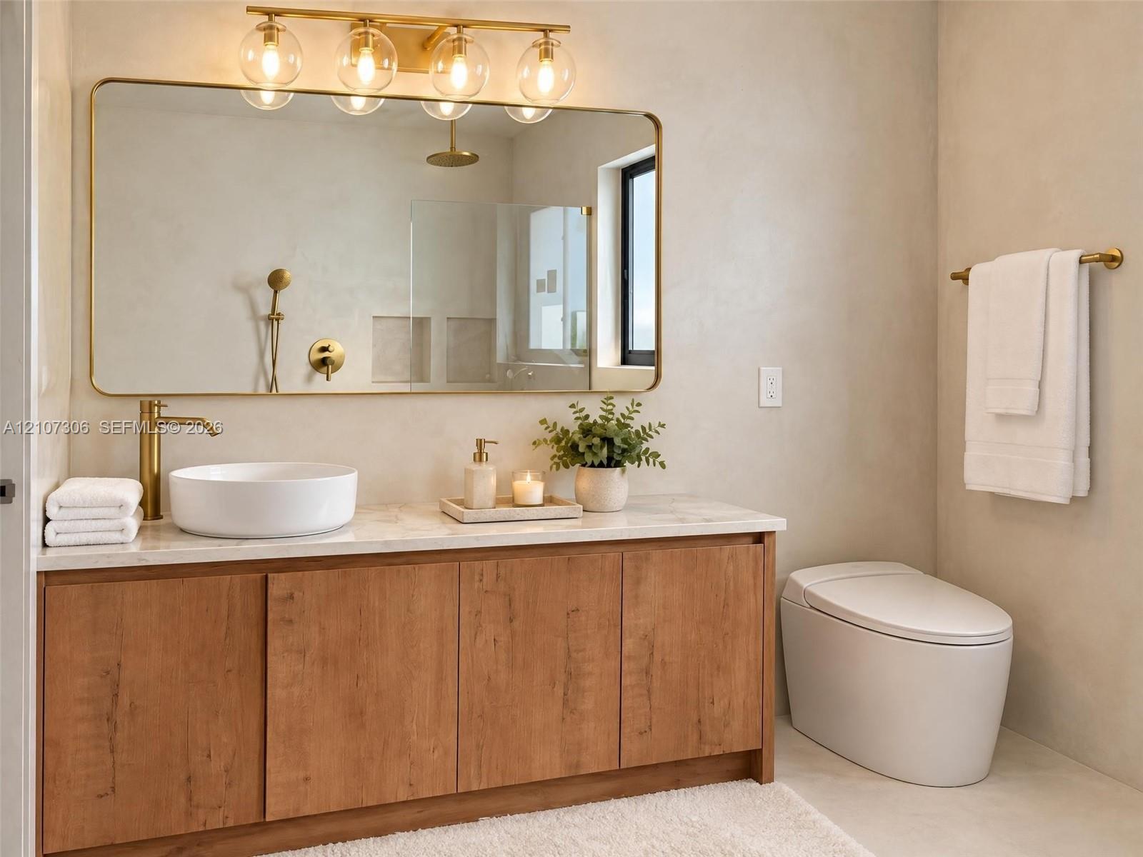 Bathroom vanity featuring a wood-finish cabinet, stone-top surface, vessel sink, and brass fixtures, complemented by a large gold-framed wall mirror with multi-globe light fixture