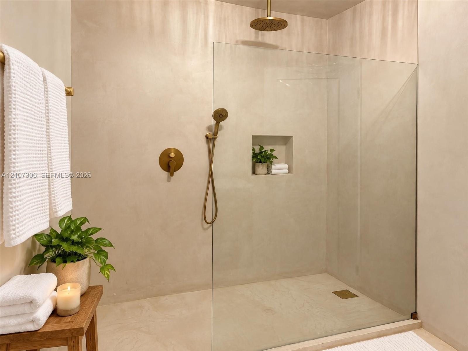 Walk-in shower featuring a seamless glass enclosure, monochromatic wall finish, brass-tone rain showerhead, matching hand-held sprayer, and a built-in recessed niche