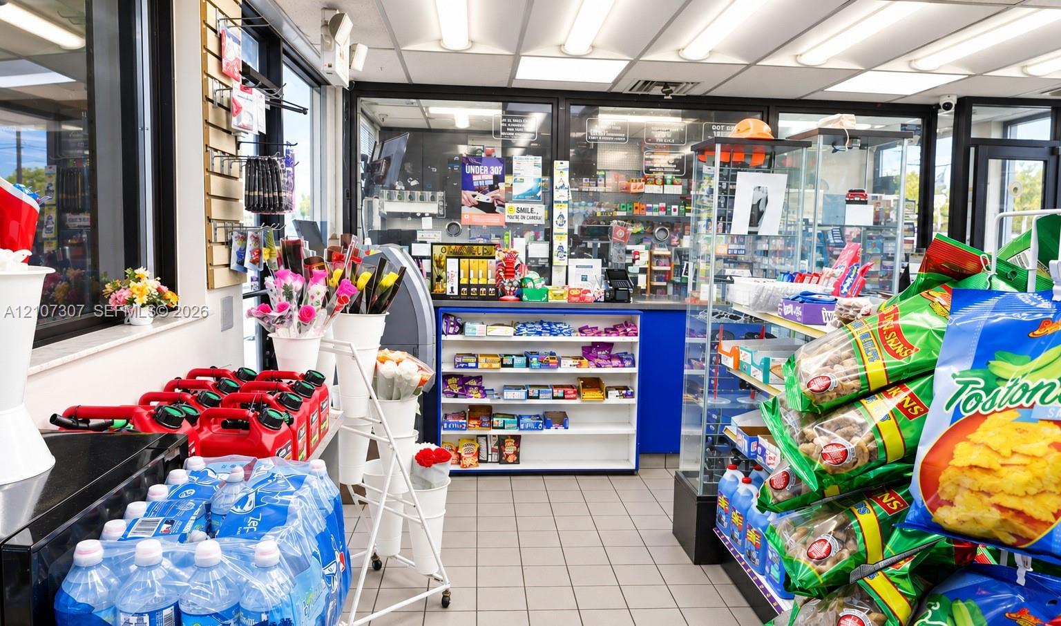 Commercial interior featuring ceramic tile flooring, built-in service counter with integrated shelving, overhead recessed lighting, and large windows with aluminum framing