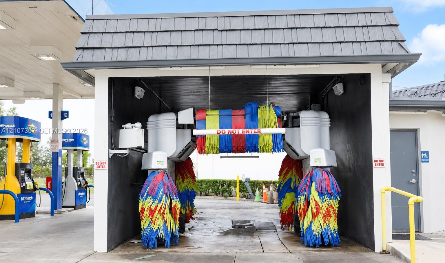 Automated car wash bay featuring an integrated brush system, overhead gabled roof structure, and concrete flooring