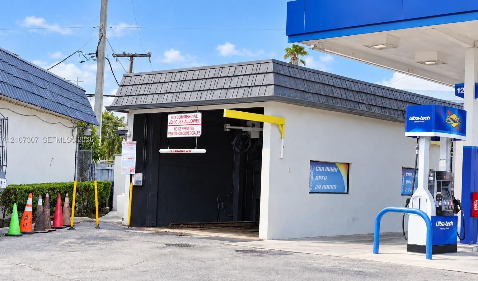 Automated car wash facility featuring a dedicated drive-through bay, light-colored stucco exterior, and multi-faceted shingle roof