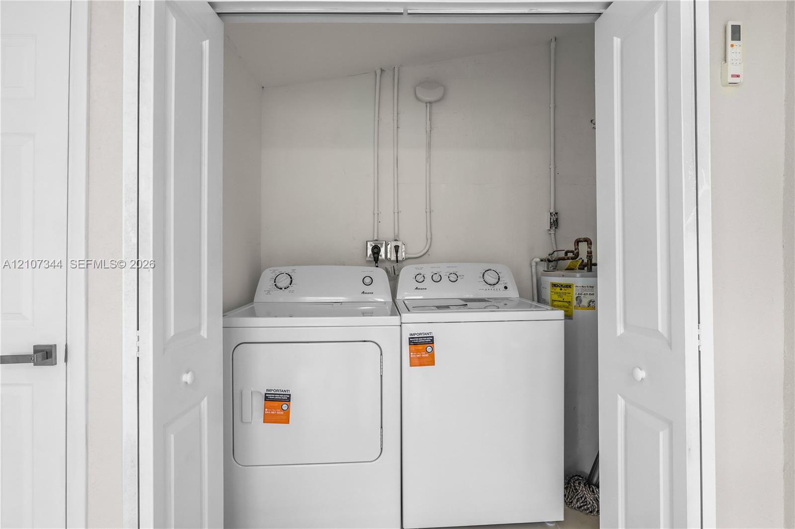 Laundry closet featuring bifold doors, top-load washer, dryer, and an integrated water heater