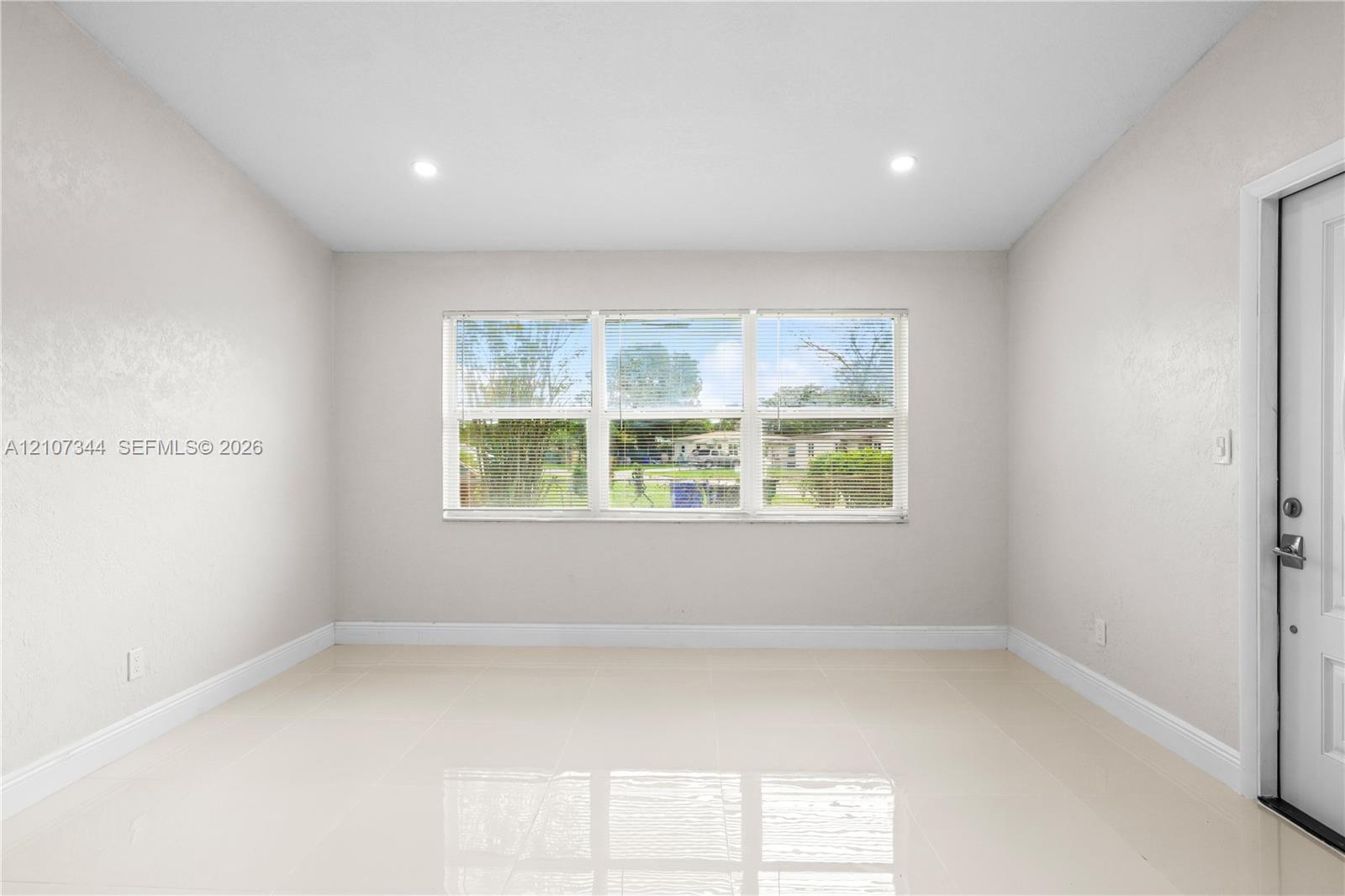 Neutral-toned interior featuring large-format tile flooring, recessed ceiling lighting, and a triple-pane window