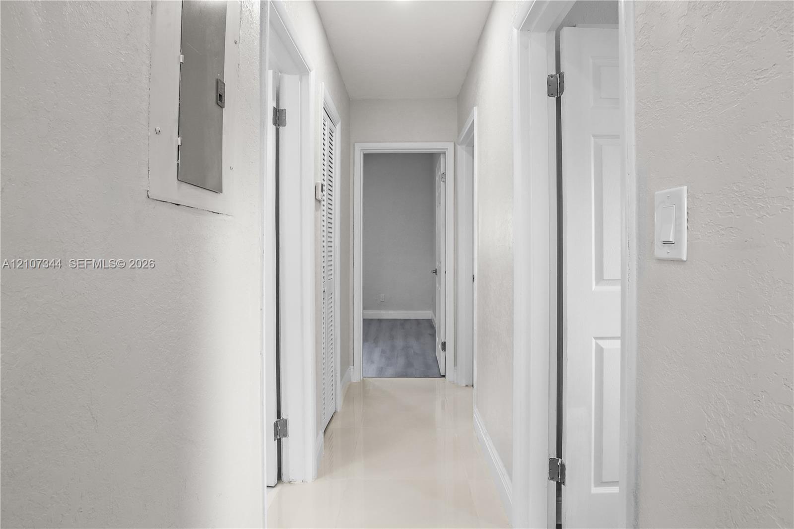 Hallway featuring neutral wall paint, multi-panel interior doors, louvered closet doors, and smooth-surface flooring