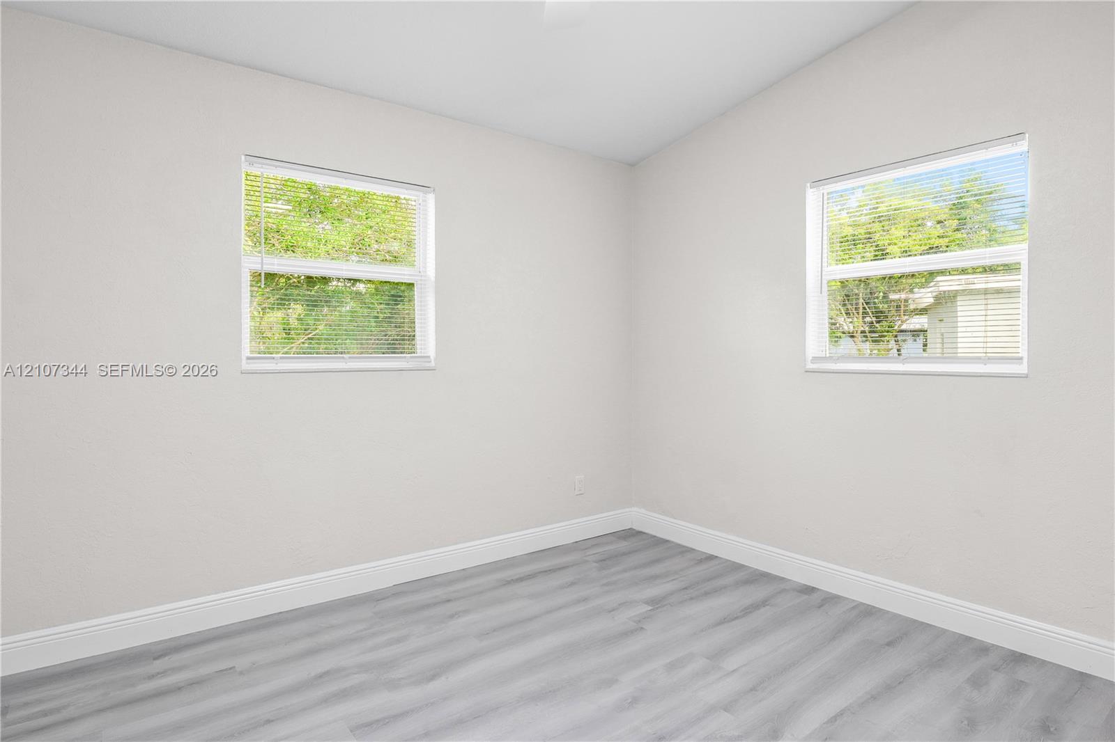 Neutral-toned interior space featuring wood-finish flooring and two double-hung windows