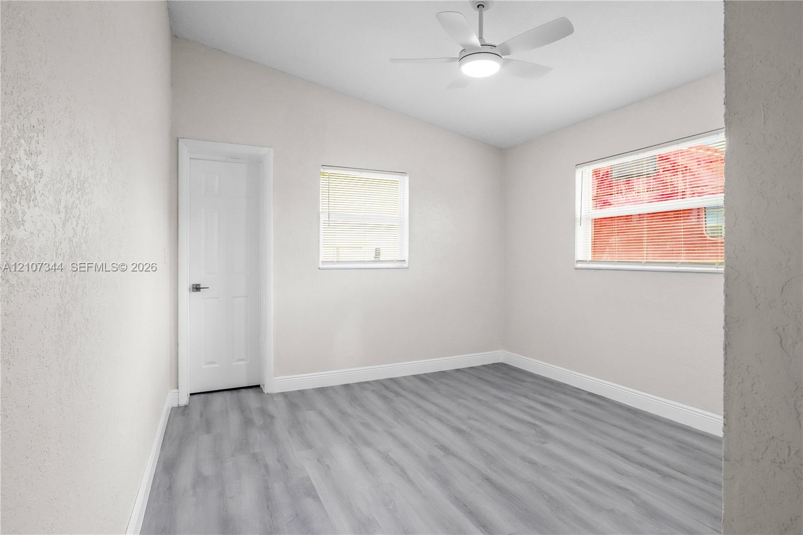 Interior space featuring vaulted ceilings, wood-finish flooring, two windows, and an integrated ceiling fan with light fixture