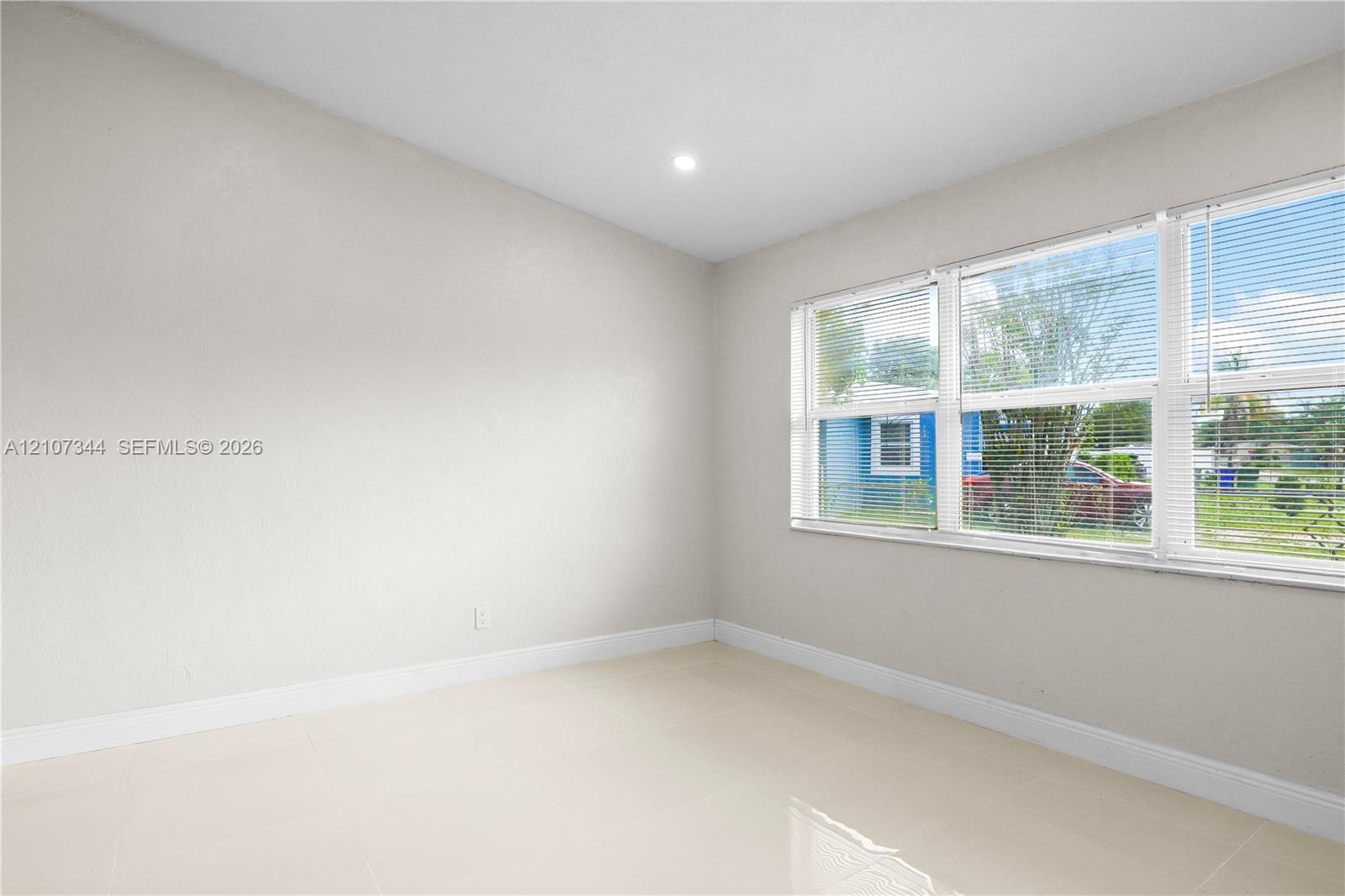 Interior space featuring neutral wall paint, polished tile flooring, and multiple windows with installed blinds