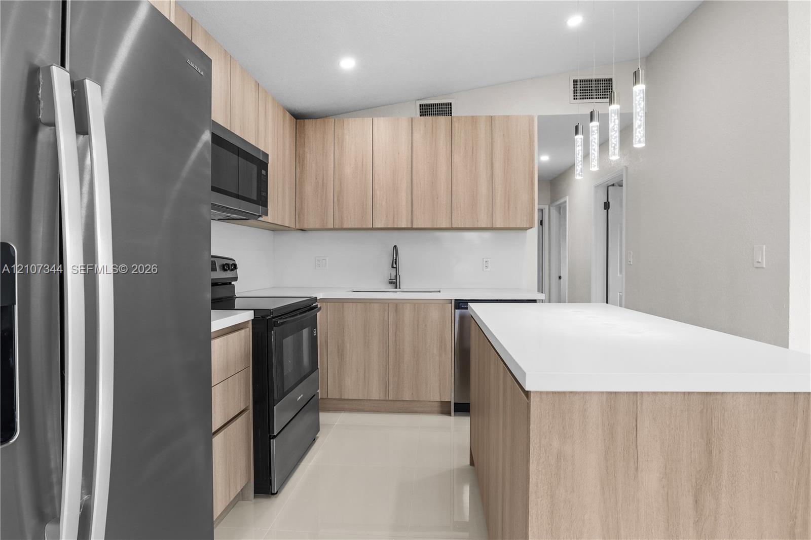 Kitchen featuring flat-panel wood-finish cabinetry, white countertops, stainless steel appliances, tile flooring, and multi-pendant lighting