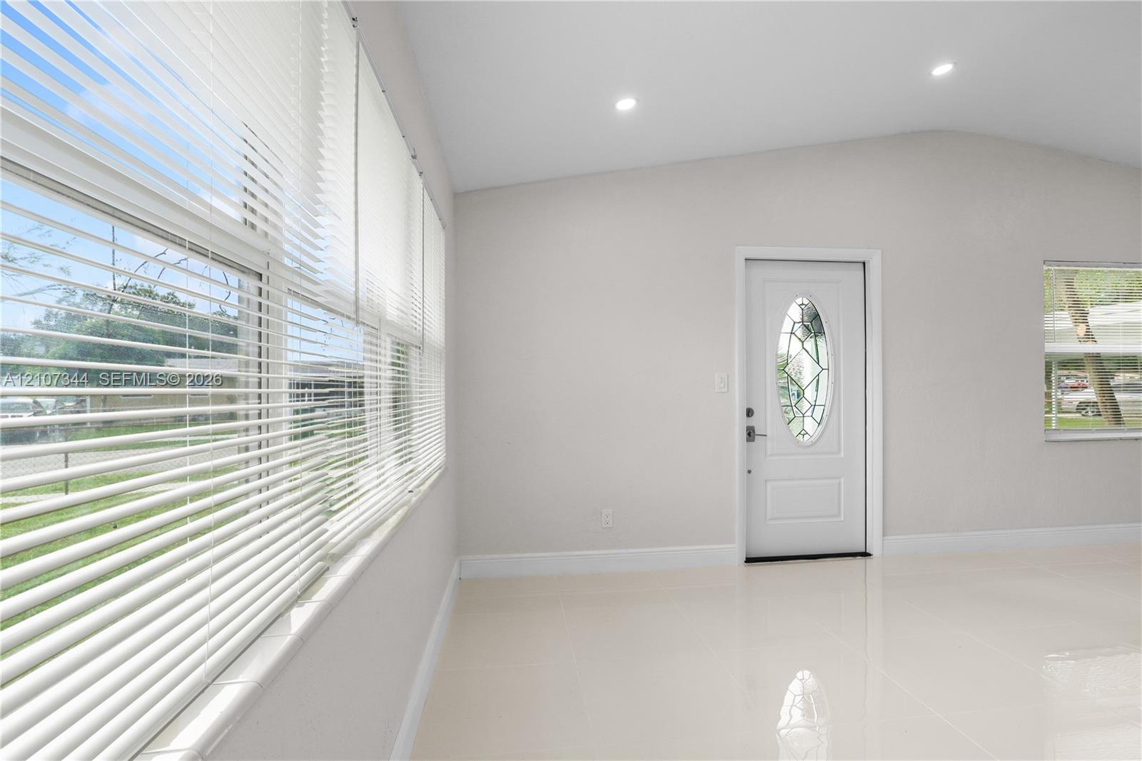 Interior space featuring large-format tile flooring, recessed lighting, and a front entry door with an oval decorative glass insert