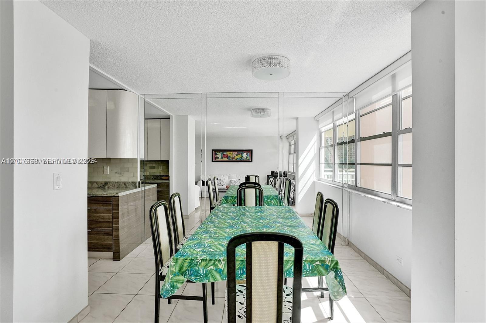 Multi-pane windows, mirrored wall, tile flooring, and custom cabinetry featuring high-gloss upper cabinets and wood-finish lower cabinets