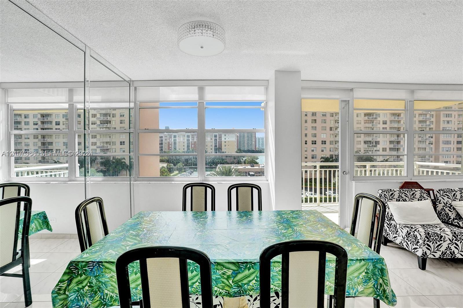 Expansive wall of windows featuring horizontal casement panes, neutral tile flooring, flush-mount tiered ceiling lighting, and a glass-enclosed wall partition