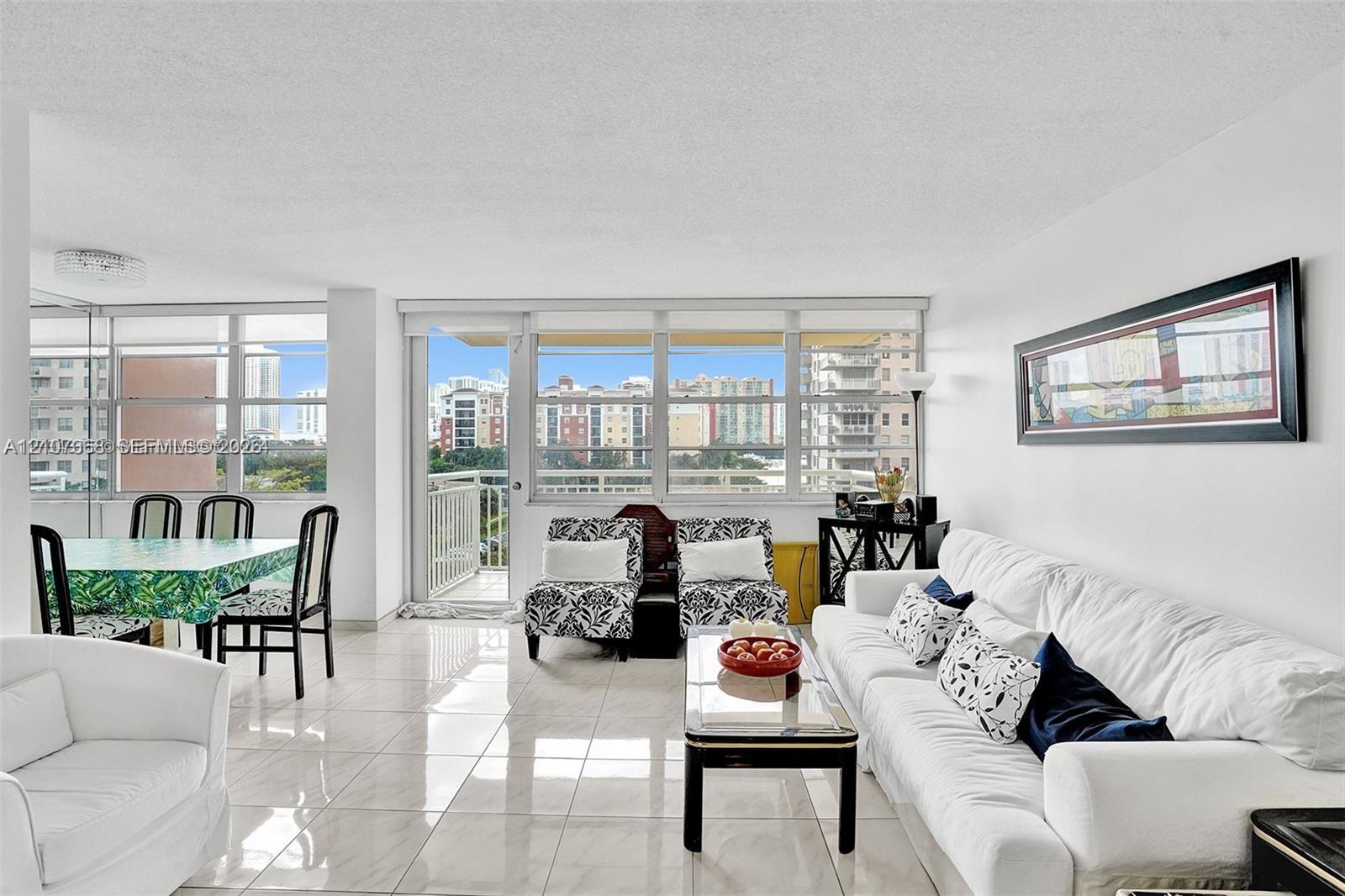 Open-concept interior featuring large-format ceramic tile flooring, floor-to-ceiling windows, and a private balcony