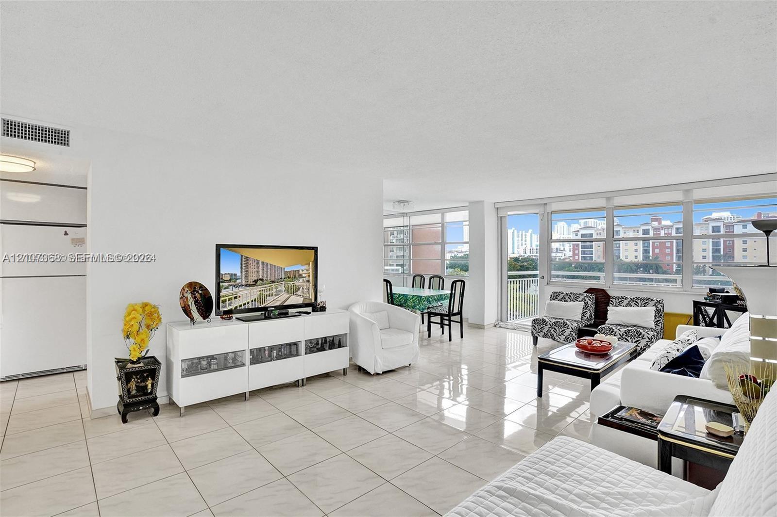 Open-concept interior featuring large-format tile flooring, an expansive wall of floor-to-ceiling windows, and access to a private balcony