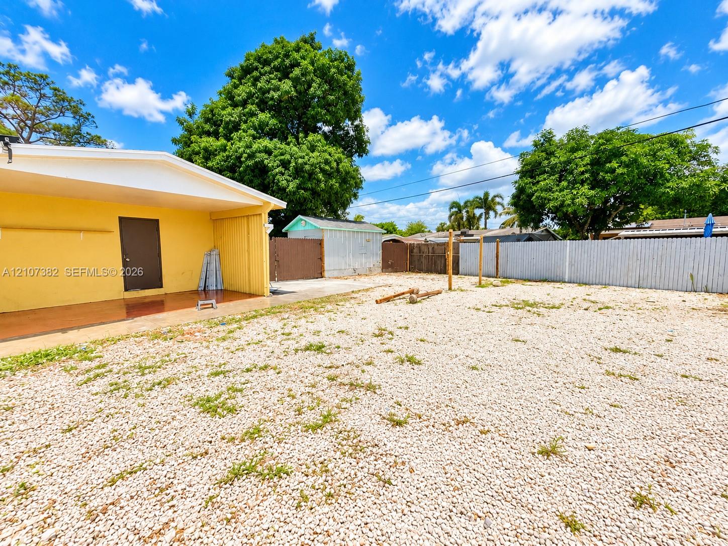 Exterior area featuring a covered patio, gravel ground cover, detached storage shed, and perimeter fencing