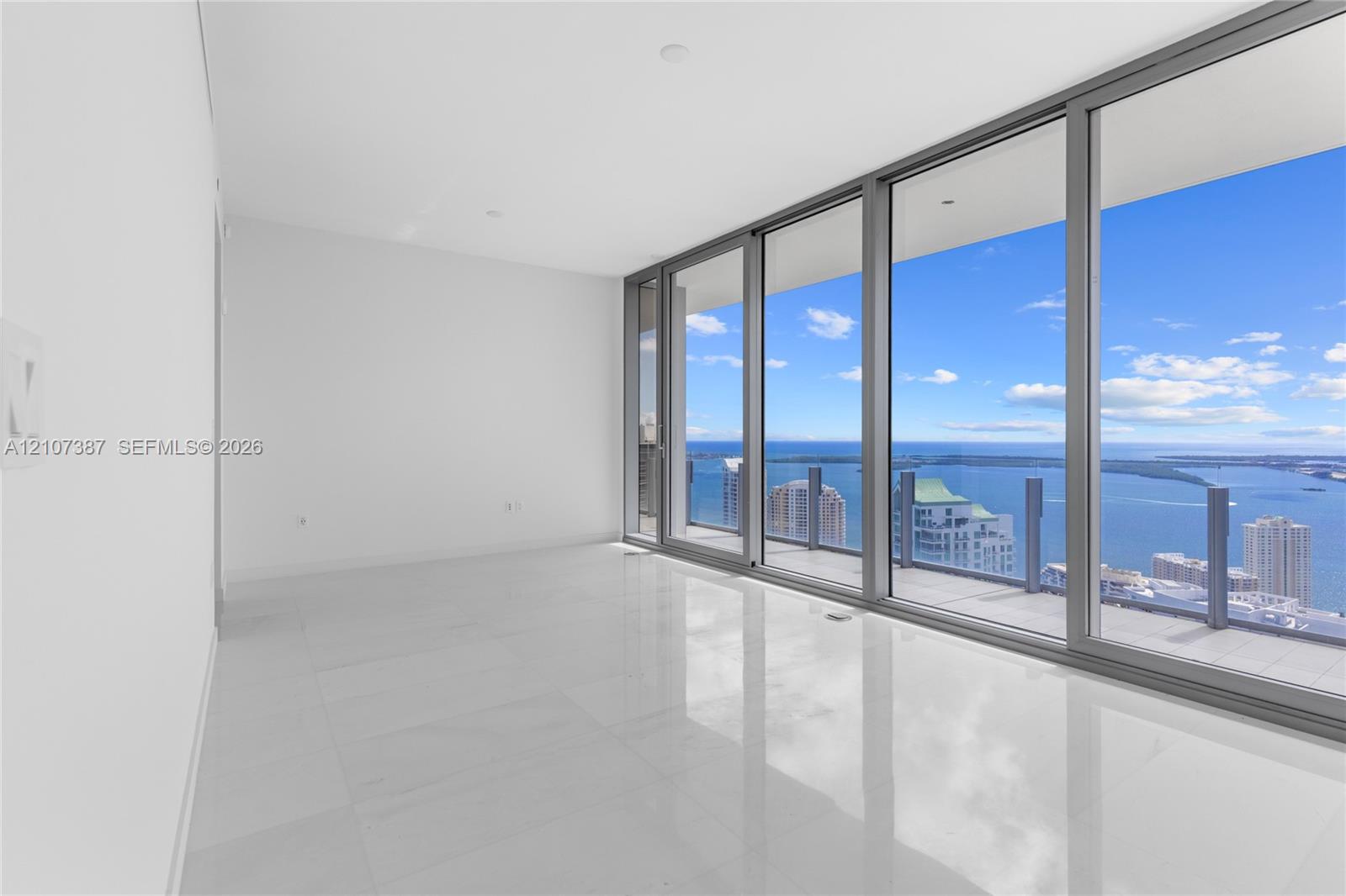 Floor-to-ceiling glass wall, polished tile flooring, recessed ceiling lighting, and expansive balcony with glass panel railing