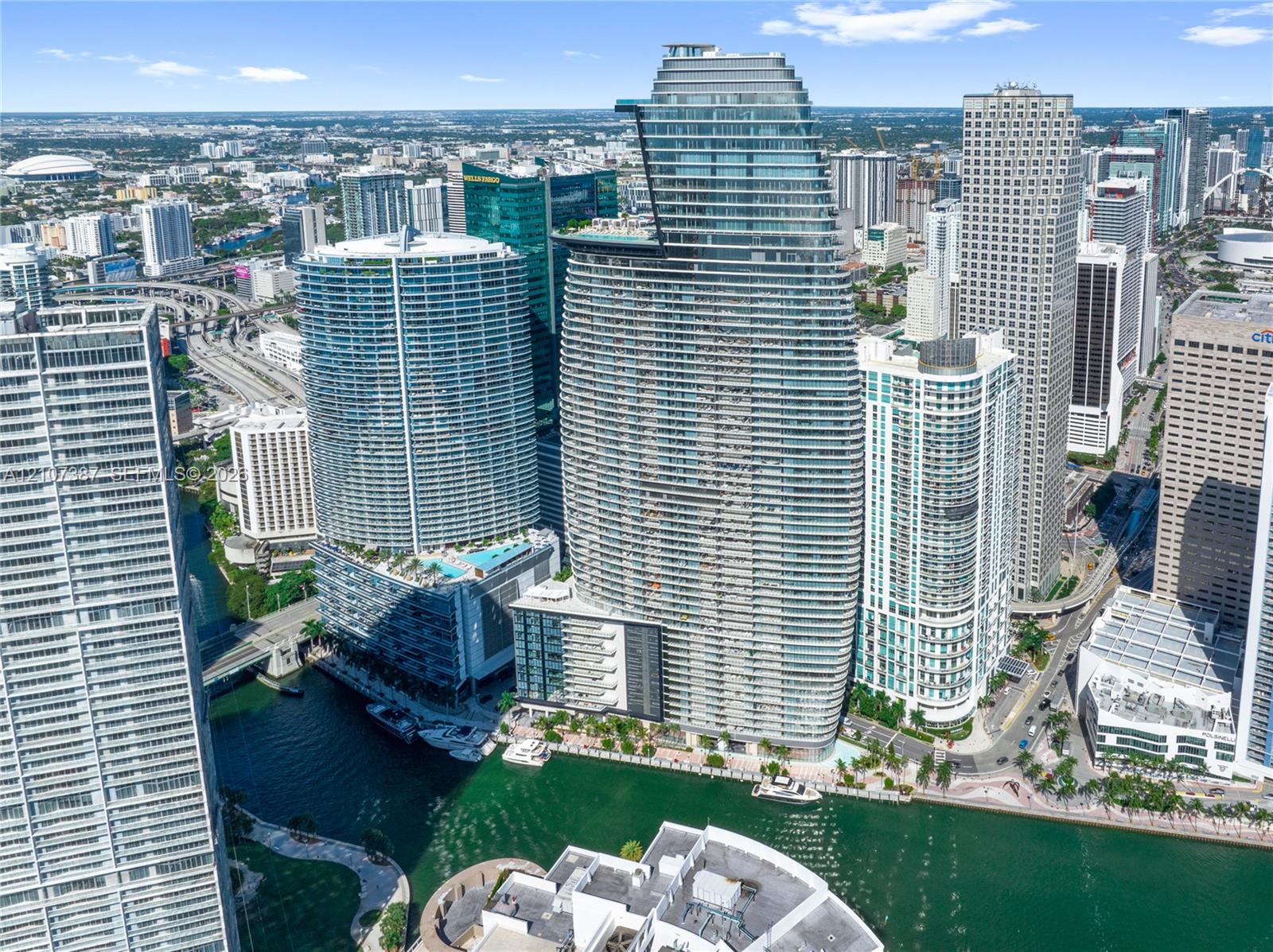 High-rise residential tower featuring a glass-curtain facade, prominent tiered architectural design, and water frontage along a canal High-rise residential tower featuring a glass-curtain facade, prominent tiered architectural design, and water frontage along a canal