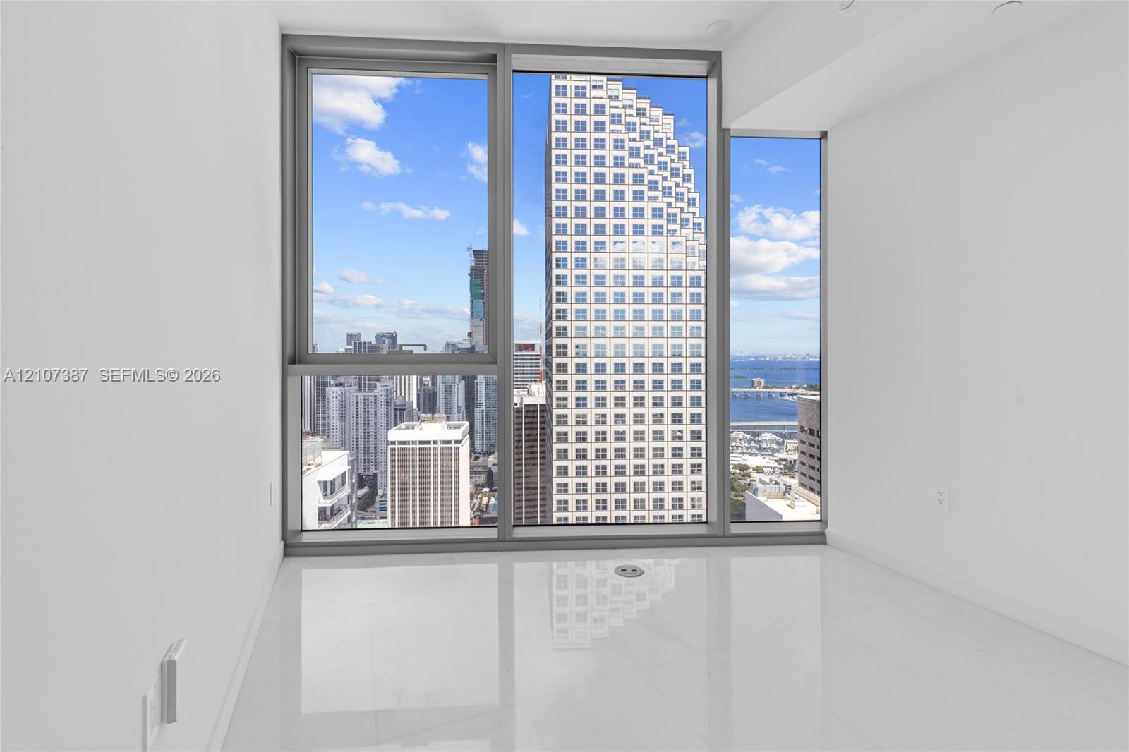 Floor-to-ceiling windows featuring metallic frames, glossy tile flooring, and urban skyscraper backdrop