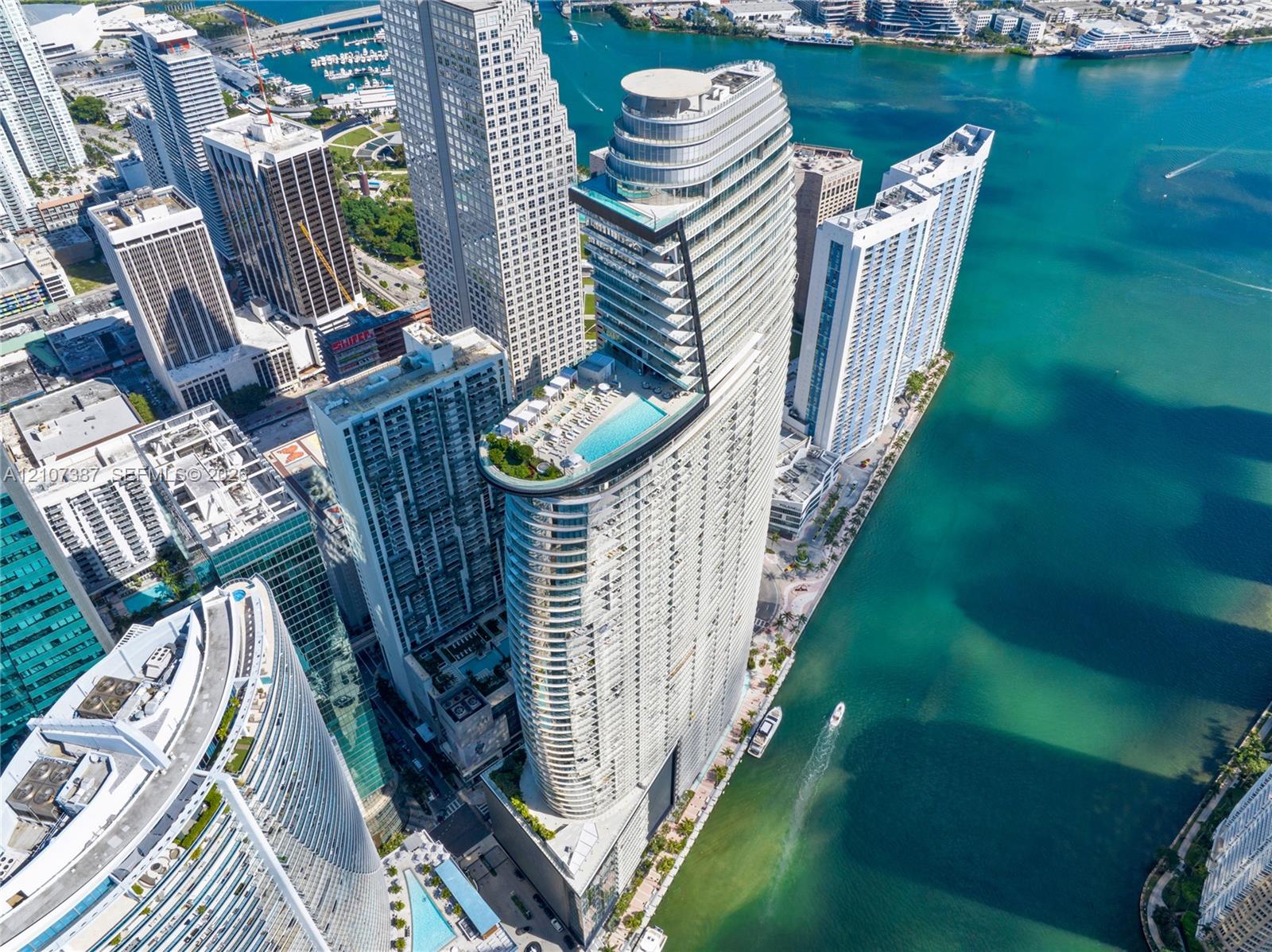 High-rise residential tower featuring a cantilevered pool deck, glass-paneled balconies, and architectural curvature situated at the waterfront